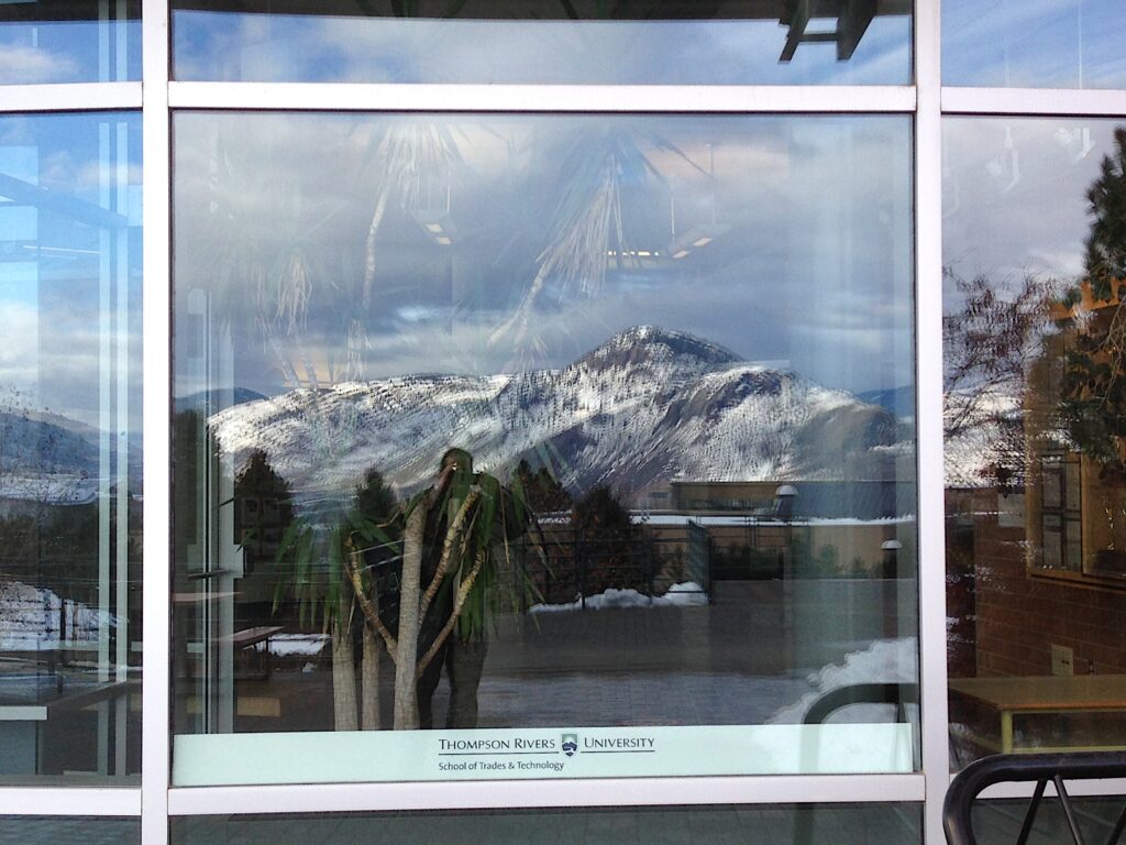 TRU students taking a selfie on campus with a mountain backdrop in Kamloops, BC